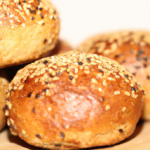 close-up of golden brown gluten-free mini buns topped with oats and seeds, keto friendly bread
