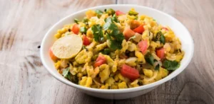 Healthy paneer bhurji garnished with fresh coriander, tomatoes, onions, and a lemon wedge in a white bowl on a wooden table